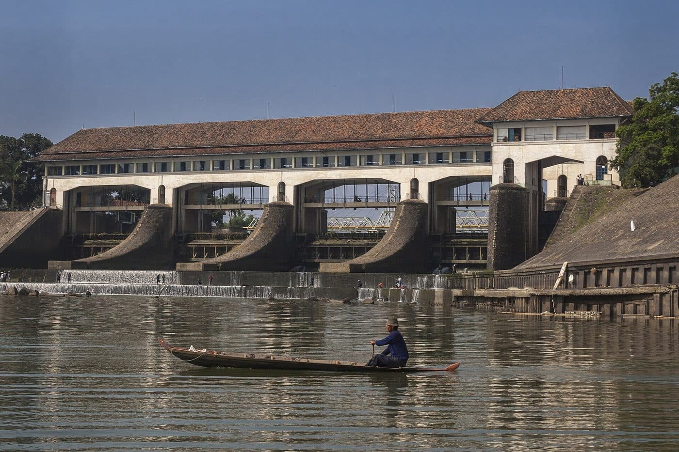 Bangunan bendung beton melintang di sungai dengan pintu-pintu air.